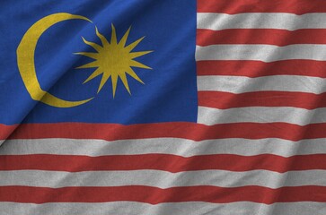 Malaysia flag depicted on folded wavy fabric of old cloth close up