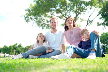 Fototapeta premium Happy family relaxing together at the park, caucasian family with father, mother, and children walking at the park.