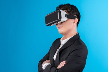 Smiling Asian businessman looking thorough VR connecting to business world report in futuristic metaverse, analyzing innovation technology ads in virtual reality isolated blue copyspace. Contrivance.