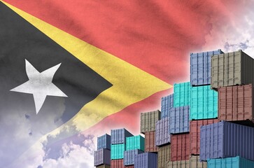 Timor Leste flag and big stack of shipping cargo containers in docks with sky background close up