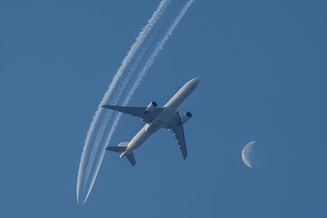 Fototapeta premium A plane flying in the blue sky with half moon and trail, minimalism, high resolution photography, stock photo, professional color grading, clean sharp focu