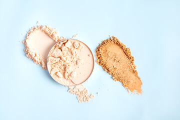 A chic example of the texture of a compact powder in a natural tone in a block and swatch on a blue background. top view. A copy space