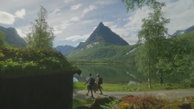 Young couple hiking along a scenic lake in Innerdalen, Norway with a mountain backdrop