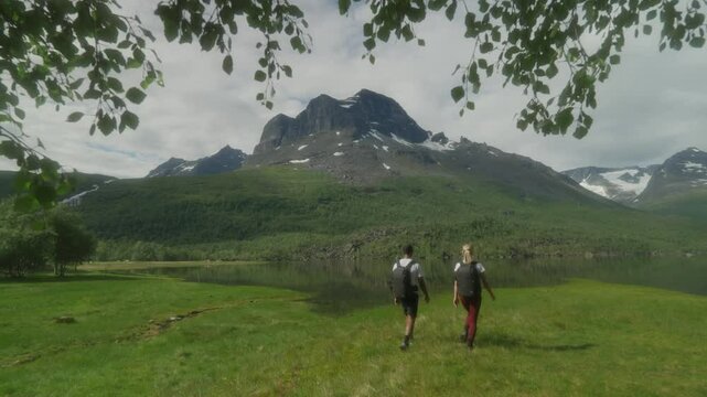 A young couple hiking in the scenic Innerdalen valley with mountains and a lake in the background