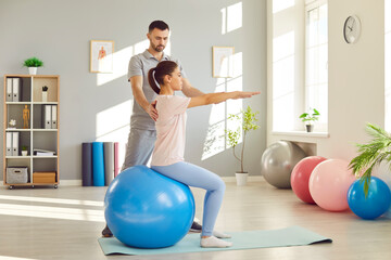 Rehabilitation spine exercise on fitness ball, spinal therapy by male physical therapist in medical...