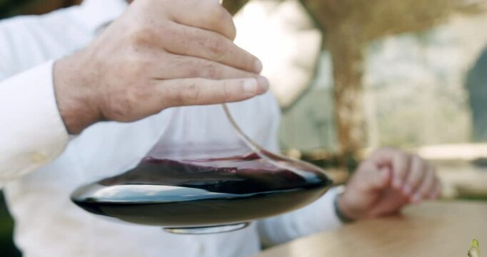 A sommelier shakes the red wine in a decanter in slow motion. Man winemaker tasting wine. Cleaning the wine of deposits and odors, before it is served. Winemaking concept.