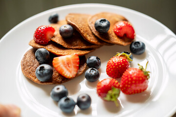 Sugar-free, gluten-free green buckwheat pancakes with strawberries and blueberries .