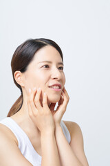 肌の状態を確かめるタンクトップ姿の女性