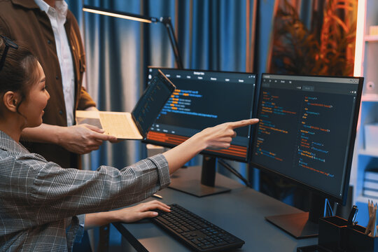 Serious of IT developers discussing intelligent website development coder system running data online two screens with laptop showing information network at neon light room at modern office. Infobahn.