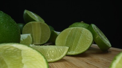 Close-up, a vibrant slice of fresh lime rests upon a rustic wooden cutting board, exuding freshness and vitality. The translucent membranes of the green lime slice placed on cutting board. Comestible.