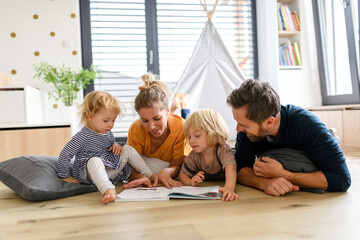 Young nuclear family playing with toys in a living room. Parents and children lying on floor,...
