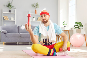 Funny man in retro sportswear is engaging in a home workout, using a dumbbell for fitness training,...