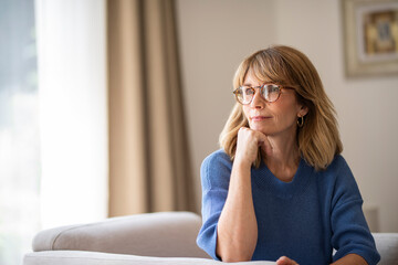 Portrait of a blond haired mid aged woman relaxing in an armchair in her modern home