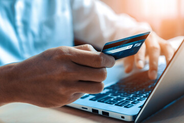 Young man use credit card for shopping payment online on laptop computer application or website. E-commerce and online shopping concept. uds
