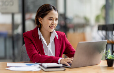 Business asian woman working on laptop, using financial calculator at modern office, analyzing business document with financial graph, market report on digital tablet, business data analysis concept