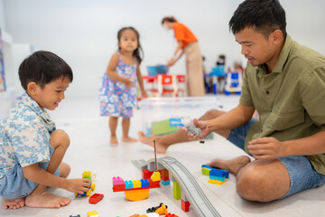 Obraz premium Dad play colorful toy block building with child boy and girl indoor playground