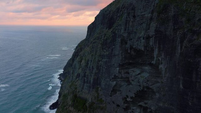 Rocky cliffs of Mercer Bay in the Waitakere Ranges at sunset.  Piha, Auckland, New Zealand.