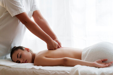 Osteopath massaging back of teenage girl lying on front in health spa