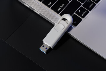 USB flash drive near the laptop mockup. 3D rendering