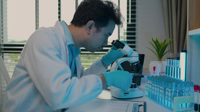 a scientist is working in the laboratory and using microscope, a chemistry is very concentration on his work, science is always in our dairy life, wearing gloves while work in the lab
