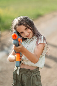 Smiling girl playing with toy gun in back yard