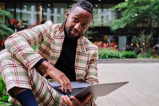 Businessman with raised eyebrow sitting with laptop