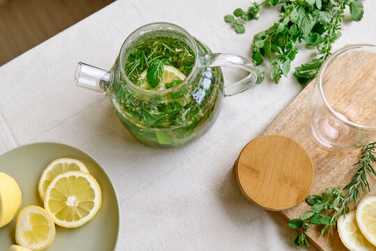 Fresh herbal tea with lemon slices and rosemary kept on table