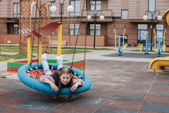 Happy girl lying and swinging on swing at playground