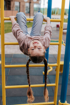 Smiling girl hanging on monkey bars in jungle gym at playground