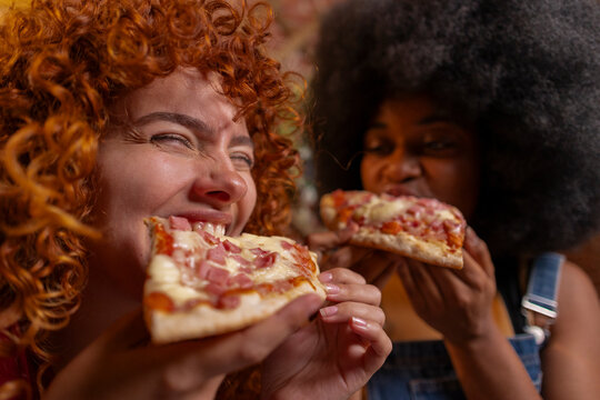 Multiracial roommates eating slice of pizza