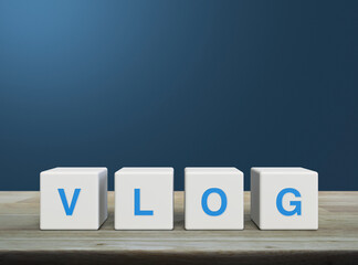 Vlog letter on white block cubes on wooden table over light blue wall, Vlog video marketing concept