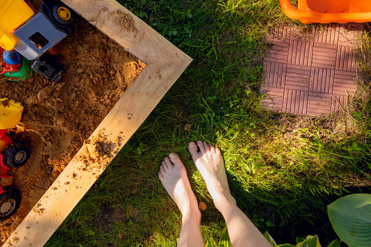 Legs of woman next to sandbox in yard