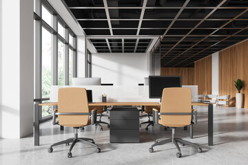 Modern office workspace with desks, monitors, and computers, featuring light wood accents, bright windows. Concept of contemporary professional workstations. 3D rendering