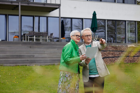 Senior couple standing in garden makong plans