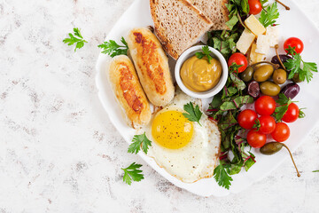 Fried egg, homemade chicken sausage, toasts and fresh salad. Keto, paleo breakfast. Top view, flat lay
