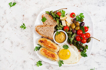 Fried egg, homemade chicken sausage, toasts and fresh salad. Keto, paleo breakfast. Top view, flat lay