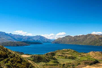 Fototapeta premium A panoramic view of a stunning mountain and lake landscape, showcasing the vastness and natural beauty of the region. The clear sky and calm lake create a peaceful and inviting atmosphere.