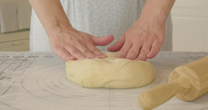 Step-by-step instructions for making cinnamon rolls. Rolling out the dough on a silicone mat. 
