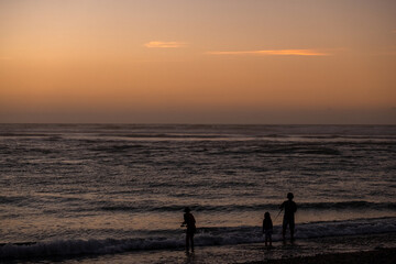 Fototapeta premium A stunning beach sunset with the silhouettes of people enjoying the view, the sky ablaze with warm colors, and the ocean waves gently rolling.