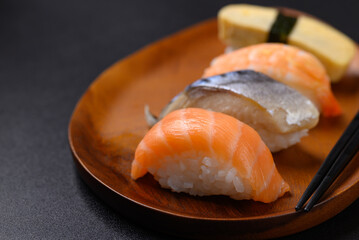 Nigiri sushi salmon, mackerel, shrimp and sweet egg (tamago) on wooden plate with chopsticks, Japanese food