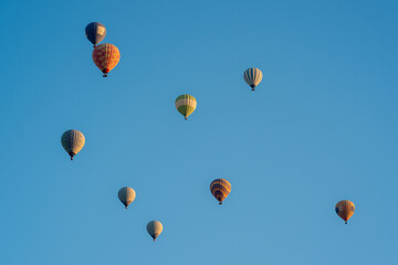 Hot air balloons in dark blue, red and yellow colors flying in a slightly cloudy blue sky
