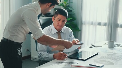 Top view of skilled businessman walking and give house design. Aerial view of architect engineer looking at blueprint and building structure at table with safety helmet and house model. Alimentation.