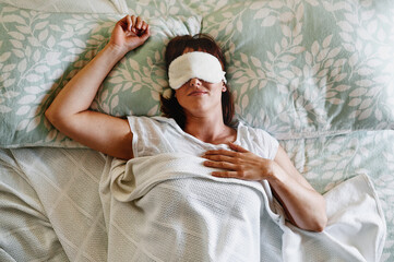 Woman, top view and mask for sleeping in bed, resting and rejuvenate body or mind on weekend in...
