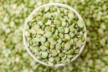 Uncooked, split, green peas in bowl. Dry peas grains. Top view