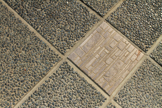 A ceramic textured tile among pebble stone floor tiles.