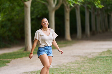 A woman is walking in a park with trees in the background