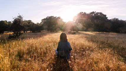 Girl Sitting in Sunny Meadow at Sunset
