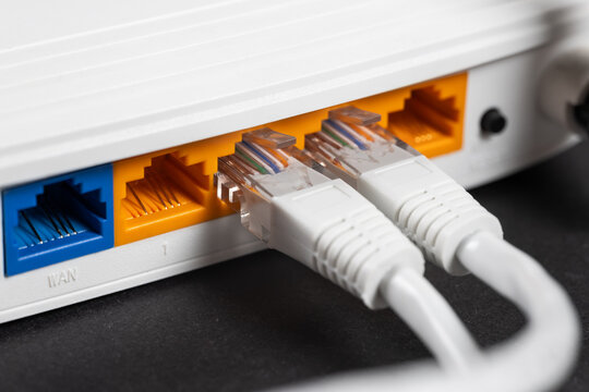 Connect an Ethernet Cable to a Wireless Router on dark. Ethernet, rj45 and electric cables, connected to router.
