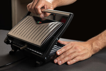 Male hand hold electric grill, on dark background