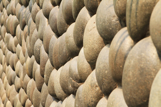 Grey round stone wall on a bright sunny day.